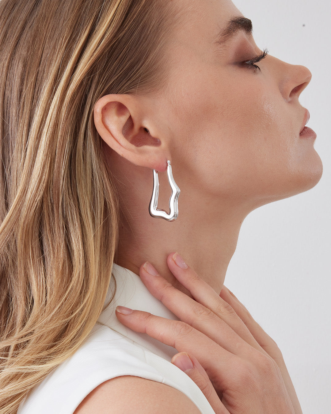 This is the product picture of organic shape elongated style hoop earrings plated in white gold in sterling silver material