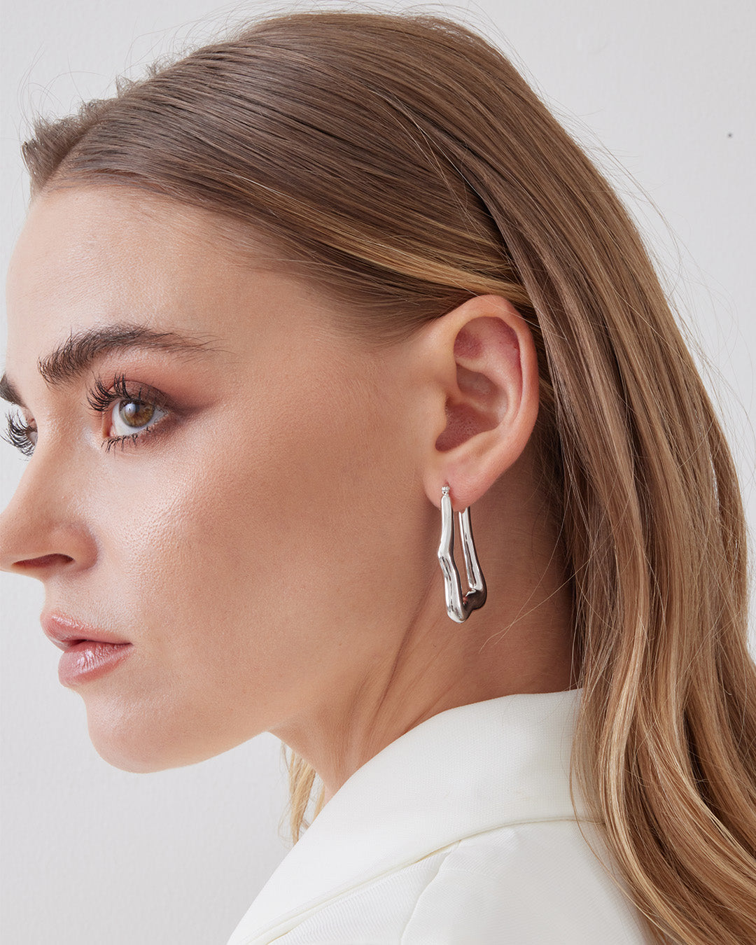 This is the product picture of organic shape elongated style hoop earrings plated in white gold in sterling silver material