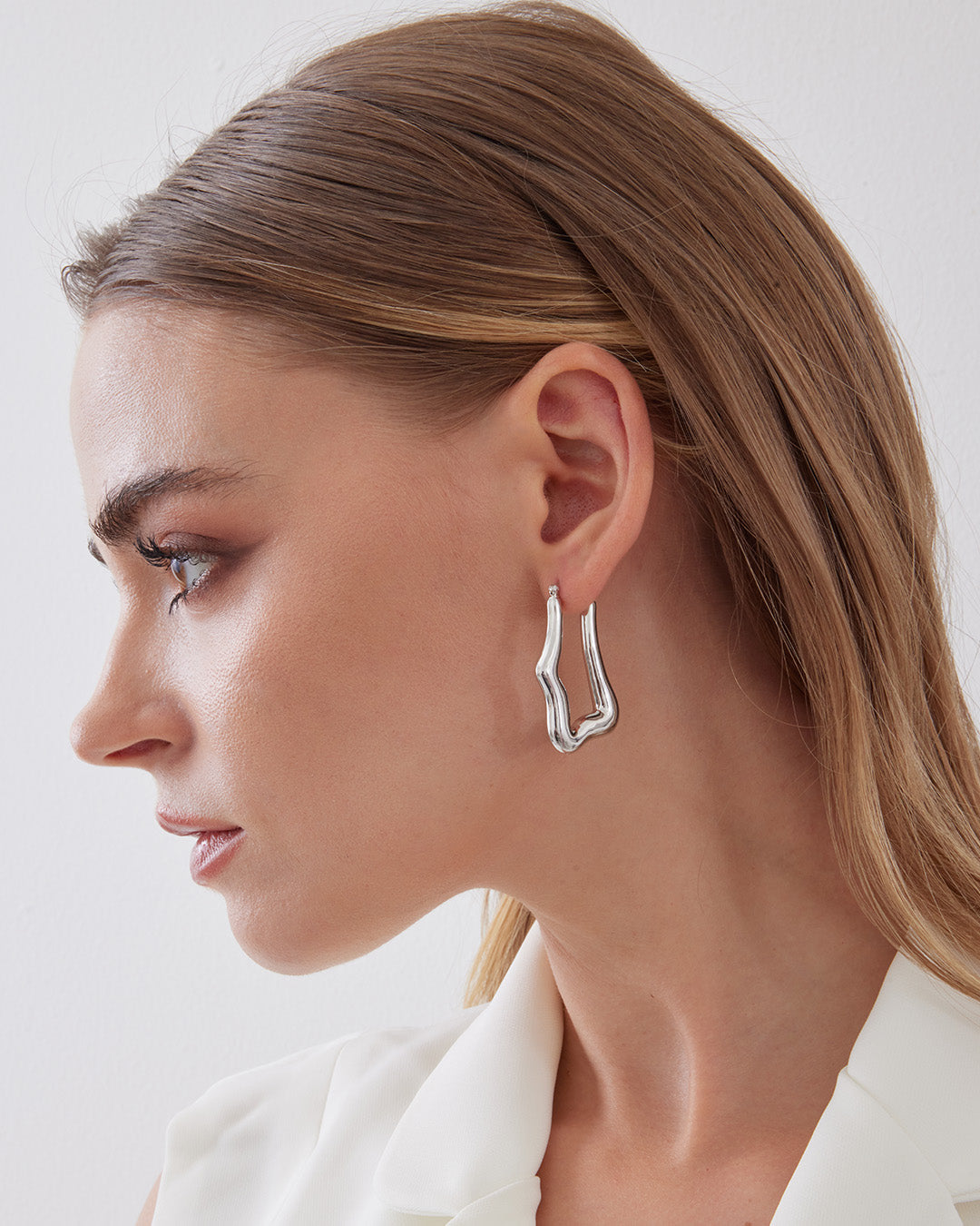 This is the product picture of organic shape elongated style hoop earrings plated in white gold in sterling silver material