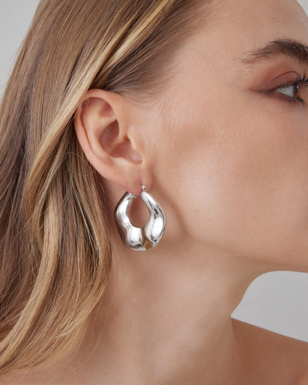 This is the product picture of organic round shape hoop earrings plated in white gold in sterling silver material