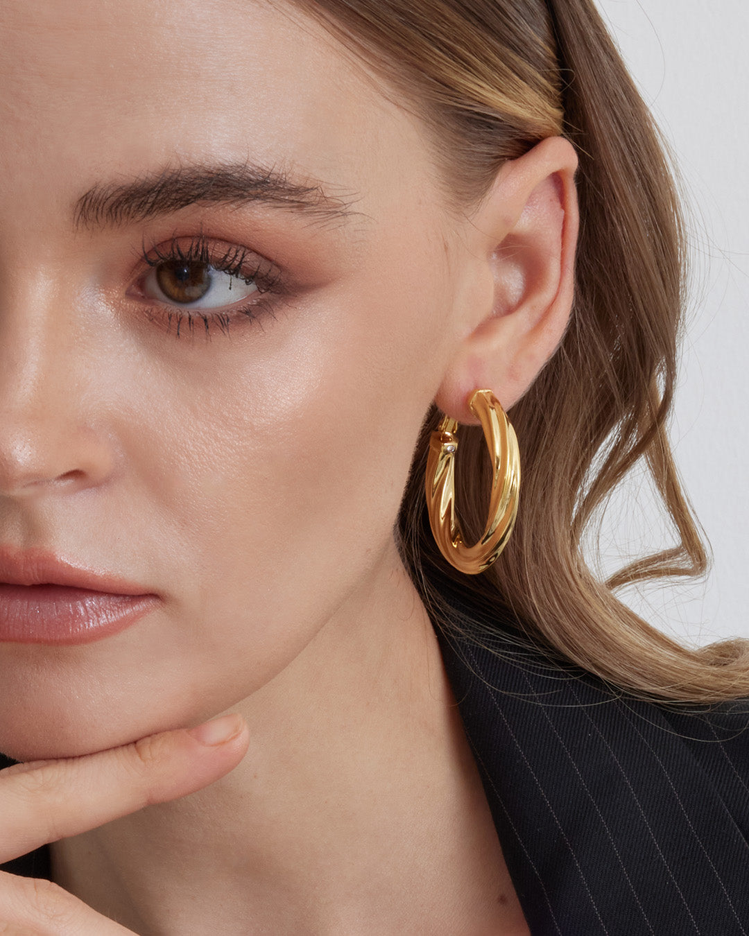 This is the product picture of luxury freeform twisted round shape hoop earrings plated in gold in sterling silver material