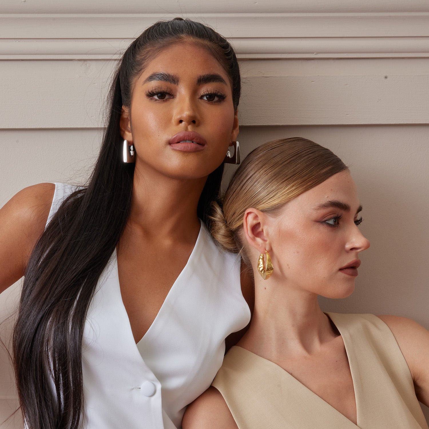 2 models wearing chunky style hoop earrings in sterling silver metal. One plated with 18K gold the other plated with rhodium