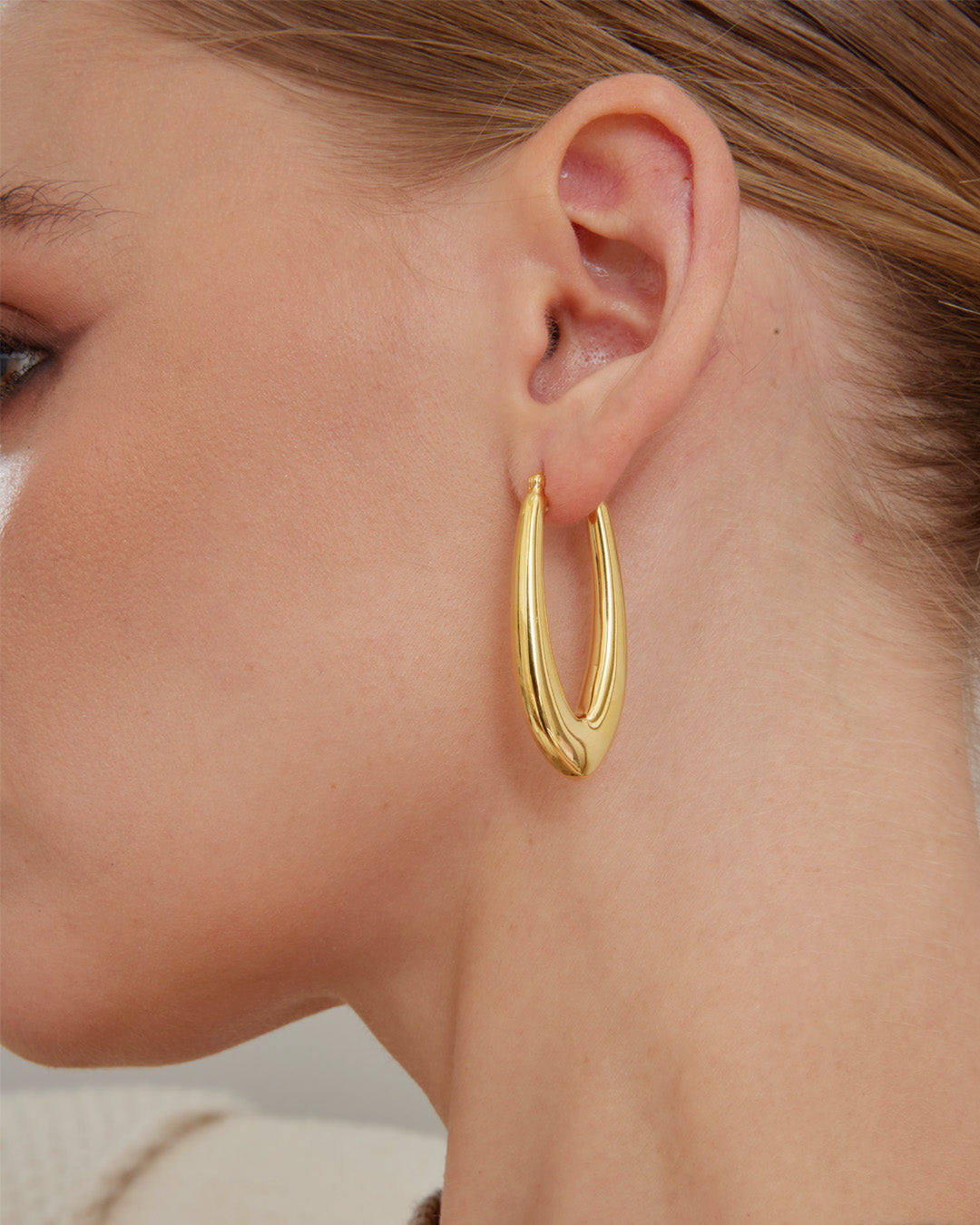 This is the product picture of elongated style hoop earrings plated in gold in sterling silver material 