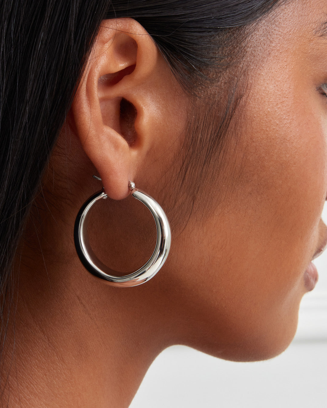 This is the product picture of round chunky hoop earrings plated in white gold in sterling silver material