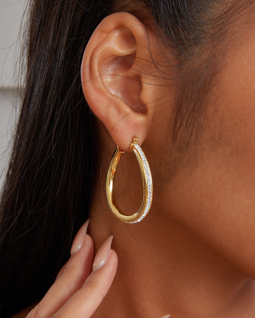 This is the product picture of a slight free form twist hoop earrings with micro pavé crystals plated in gold in sterling silver material