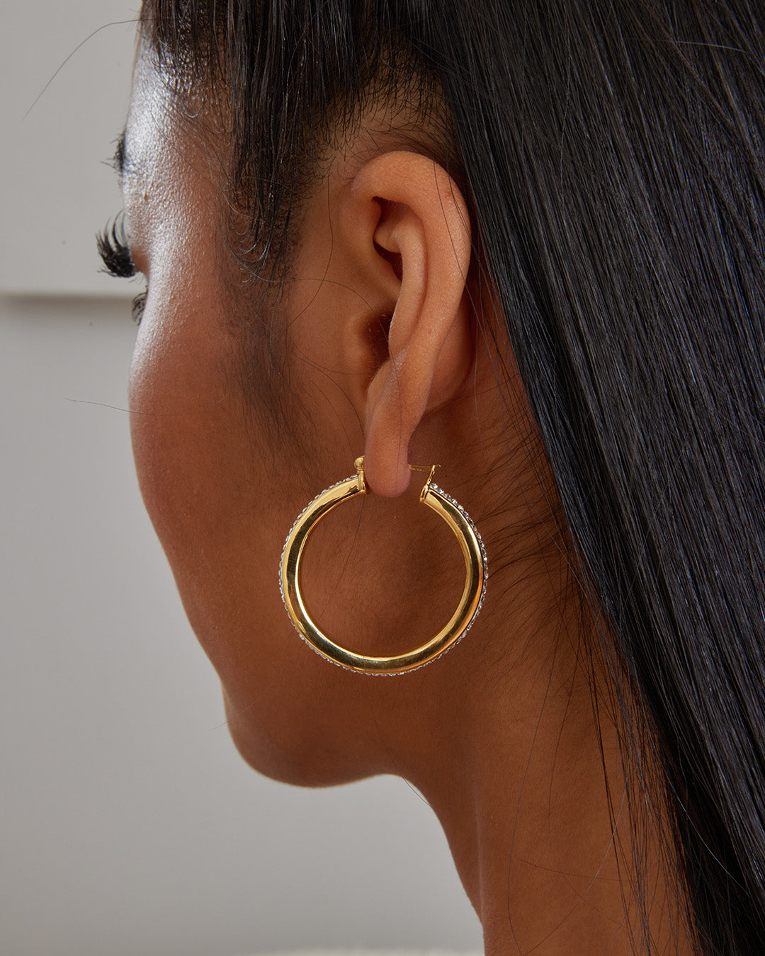 This is the product picture of a slight free form twist hoop earrings with micro pavé crystals plated in gold in sterling silver material