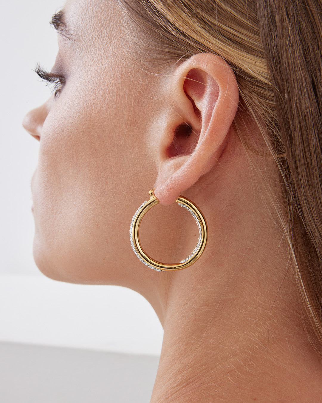 This is the product picture of elegant hoop earrings with micro pavé crystals plated in gold in sterling silver material