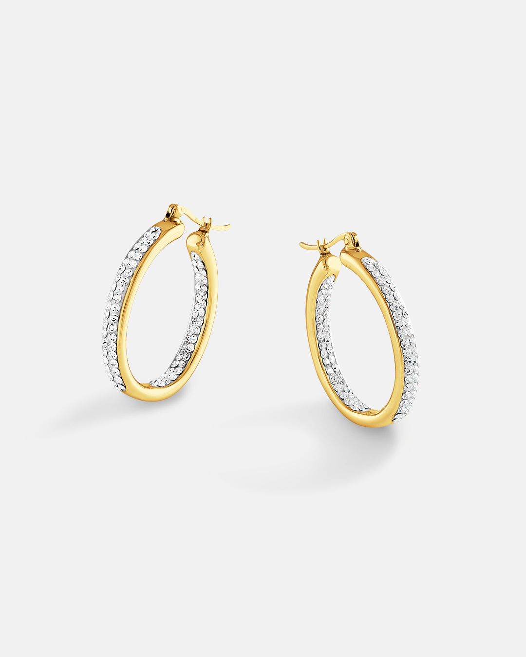 This is the product picture of elegant oval shape hoop earrings with micro pavé crystals plated in gold in sterling silver material