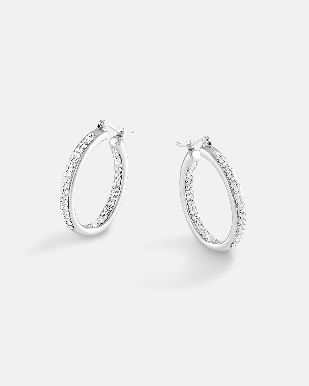 This is the product picture of elegant oval shape hoop earrings with micro pavé crystals plated in white gold in sterling silver material