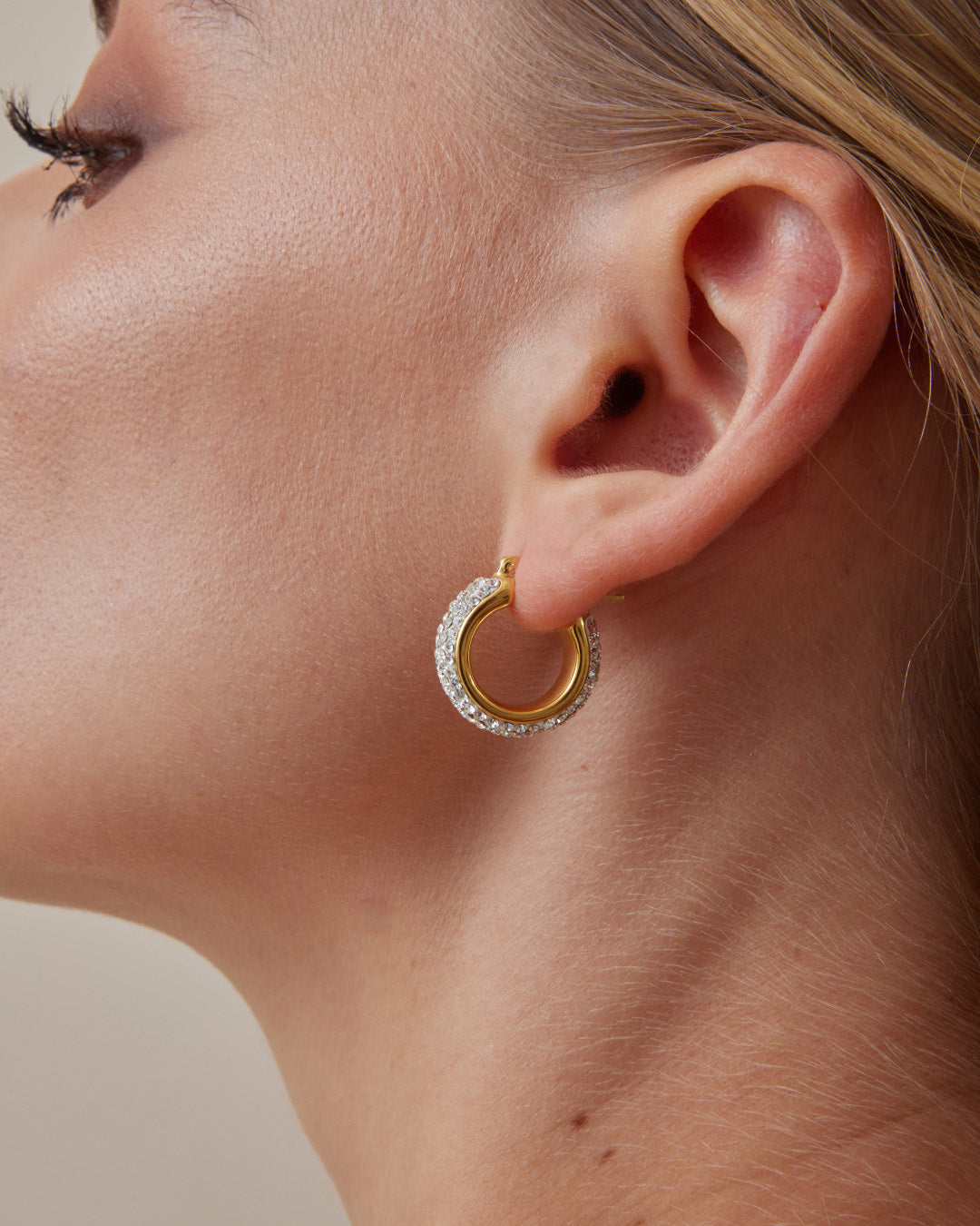 This is the product picture of small elegant hoop earrings with micro pavé crystals plated in gold in sterling silver material