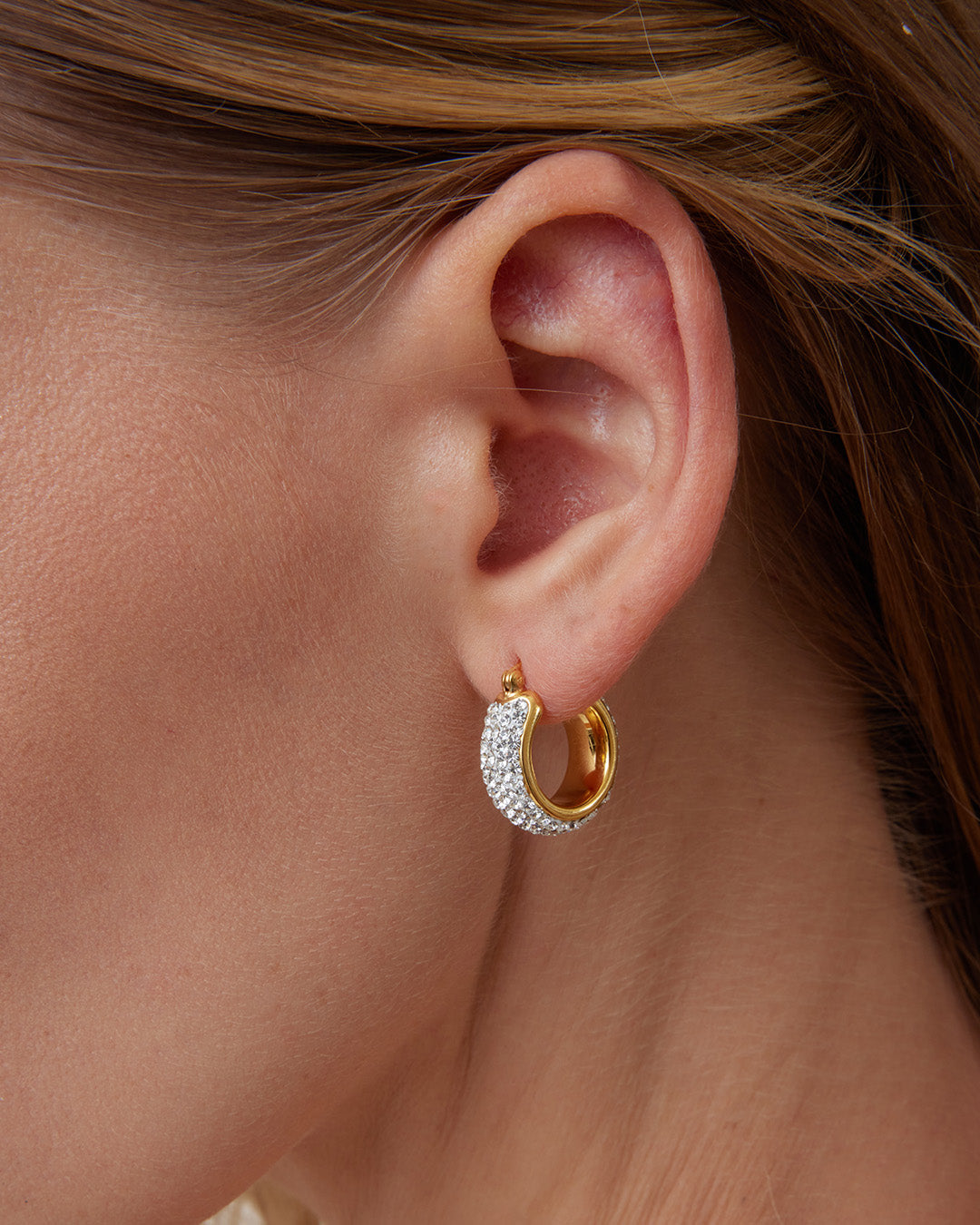 This is the product picture of small elegant hoop earrings with micro pavé crystals plated in gold in sterling silver material