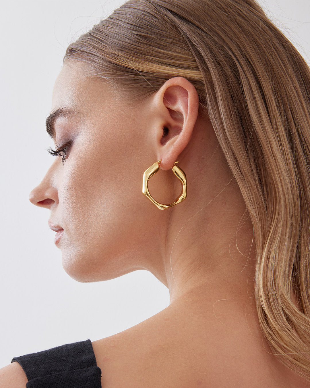 This is the product picture of heptagon shape hoop earrings plated in gold in sterling silver material