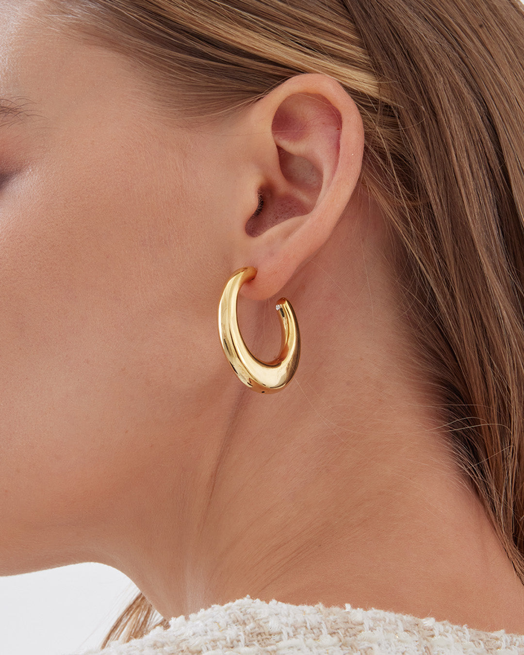 This is the product picture of organic shape elongated style hoop earrings plated in gold in sterling silver material 