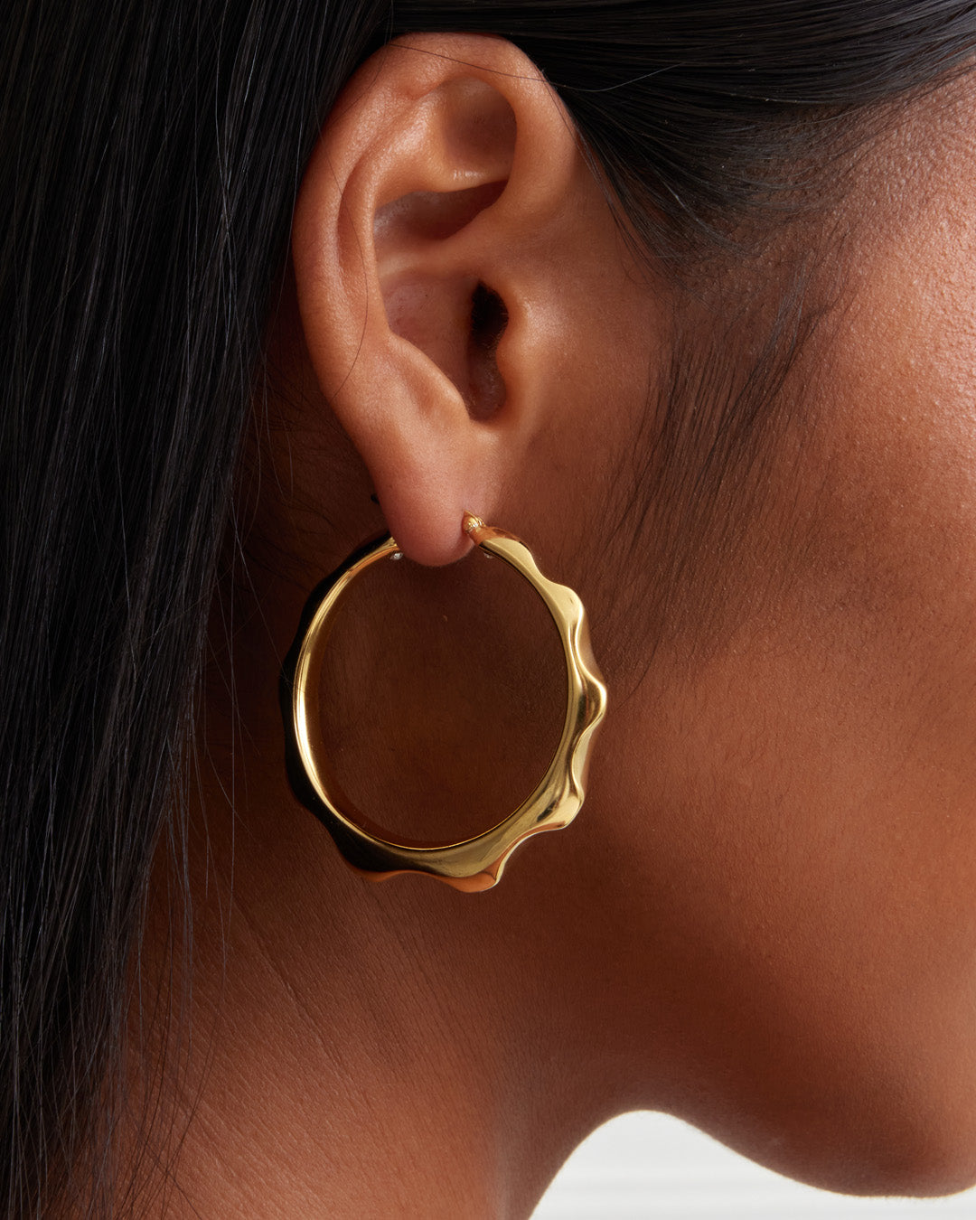 This is the product picture of freeform spiked rounded hoop earrings plated in gold in sterling silver material