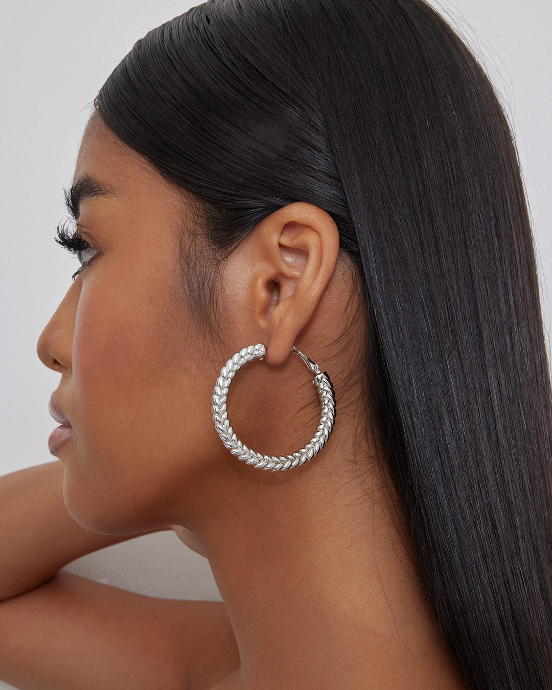 This is the product picture of flat tree leaves design hoop earrings plated in white gold in sterling silver material