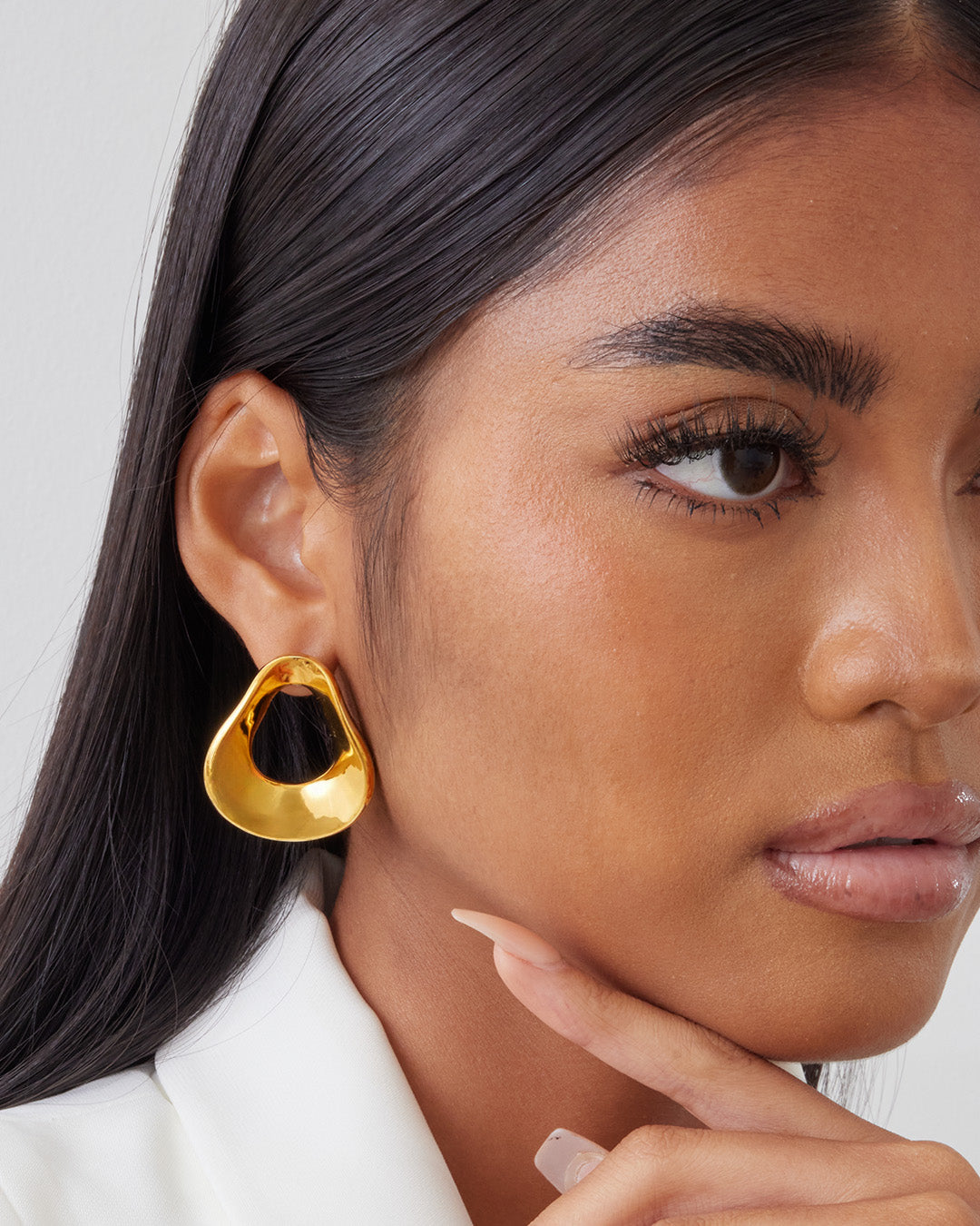 This is the product picture of an oversized freeform shape hoop earrings plated in gold in sterling silver material