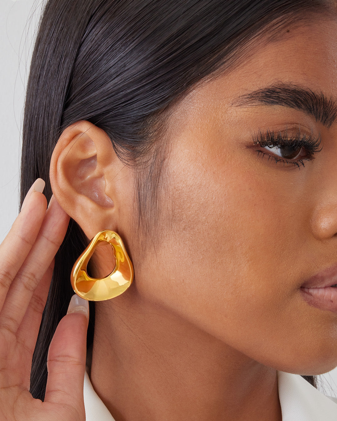 This is the product picture of an oversized freeform shape hoop earrings plated in gold in sterling silver material