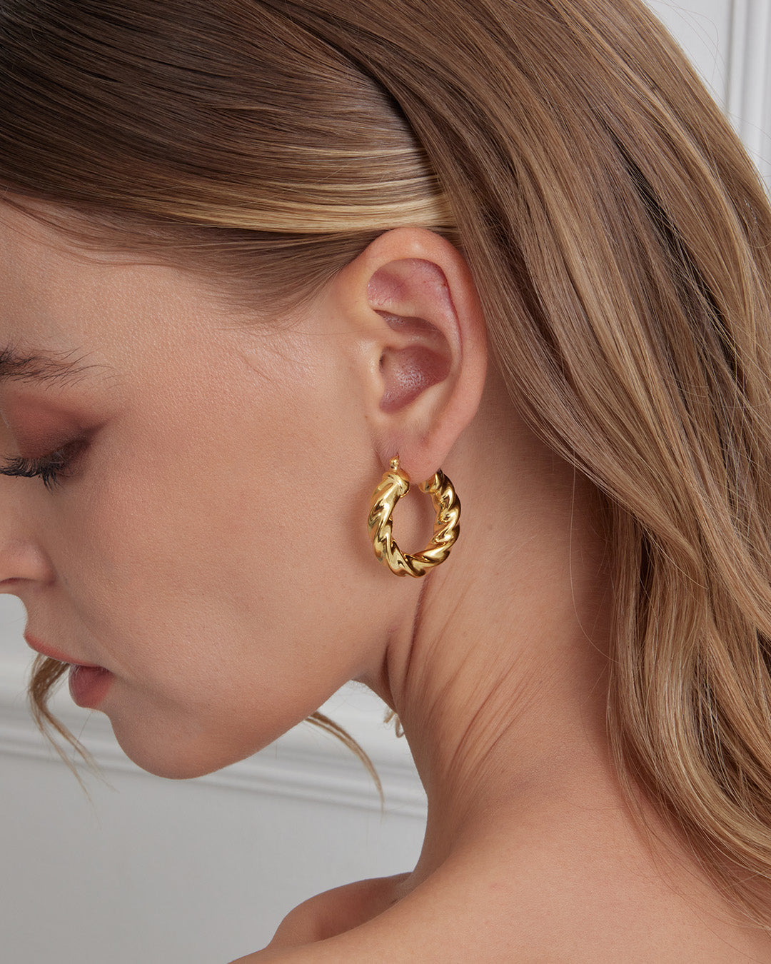 This is the product picture of modern twisted chunky hoop earrings plated in gold in sterling silver material